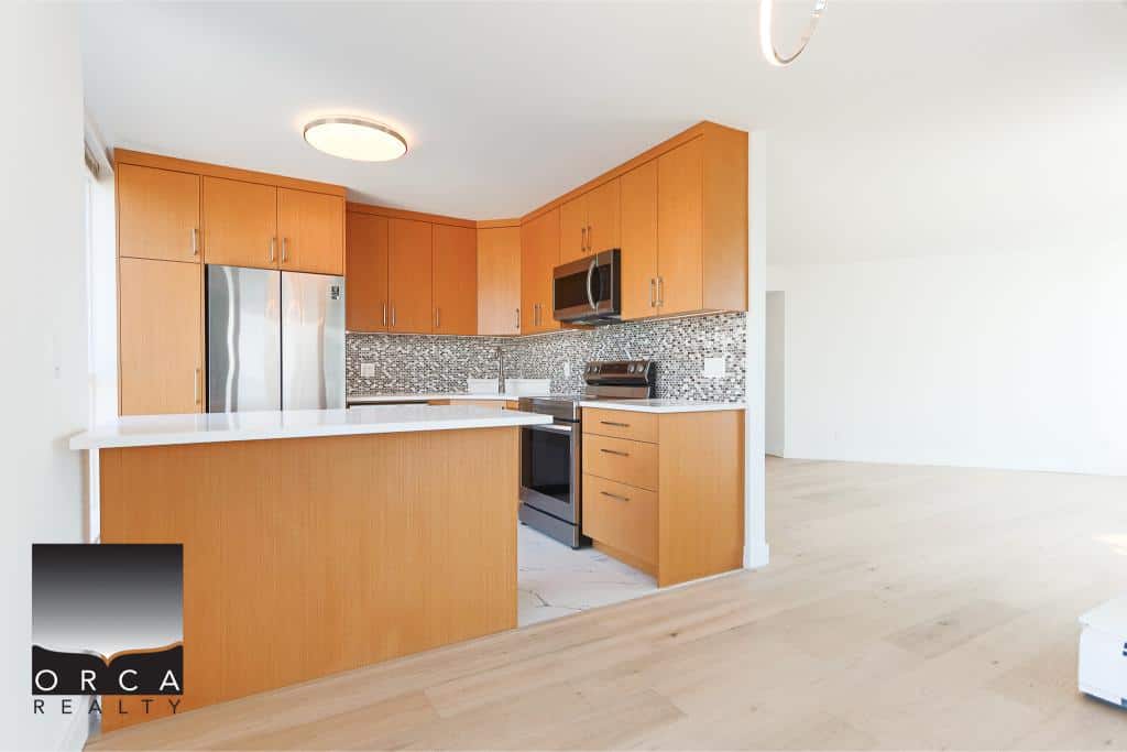 Modern kitchen with wood cabinets and stainless steel appliances in a Vancouver-area home for sale by Orca Realty Inc.