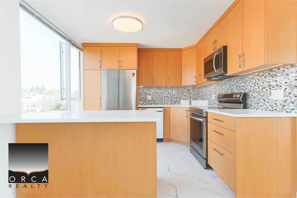Modern kitchen with stainless steel appliances, wooden cabinets, and a mosaic tile backsplash, ideal for Vancouver real estate enthusiasts.