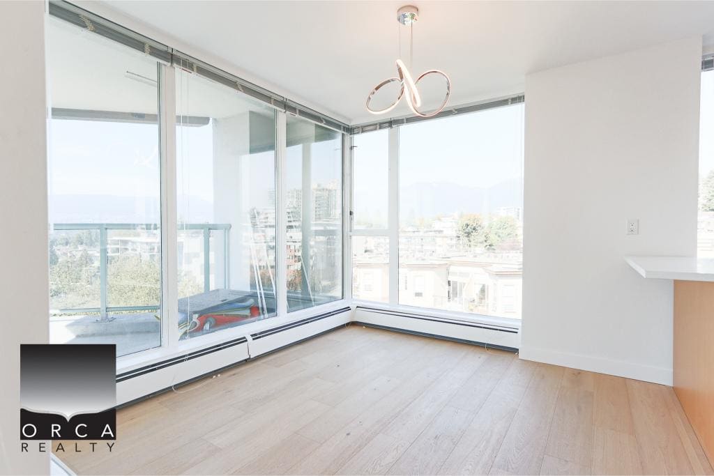 Bright modern condominium interior with large floor-to-ceiling windows overlooking city views in Vancouver, ideal for real estate listings and property showcases by Orca Realty Inc.