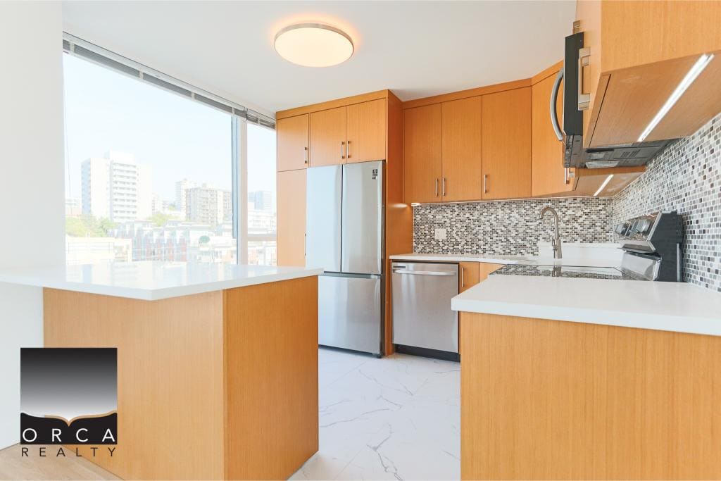 Modern kitchen with wood cabinets, stainless steel appliances, mosaic backsplash, and large windows offering city views - ideal for Vancouver real estate listings.