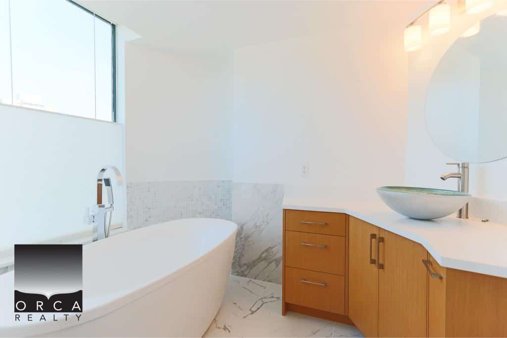 Modern bathroom with a freestanding bathtub and contemporary vanity, featuring natural light, minimalist design, and high-end finishes – perfect for upscale Vancouver Island real estate.