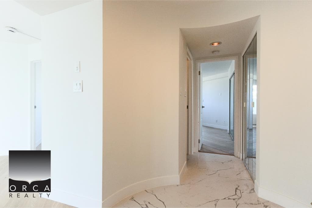 Contemporary apartment hallway with marble flooring, mirrored closet doors, and bright white walls in a modern Vancouver property.