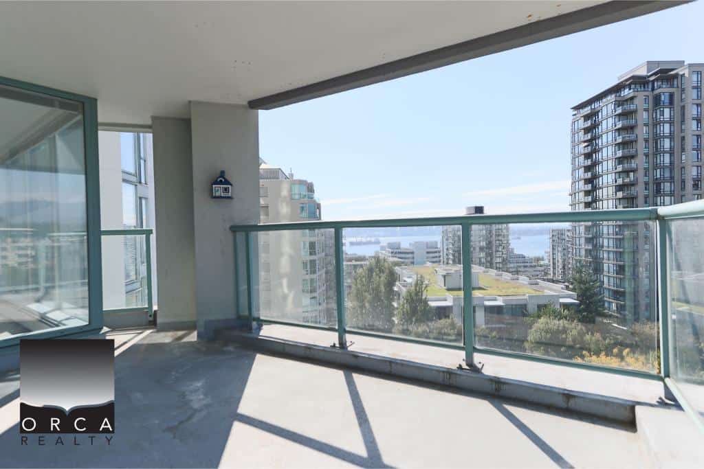 Spacious modern balcony with glass railing overlooking cityscape and water views in Vancouver, British Columbia. Ideal for relaxing and enjoying the scenic surroundings.