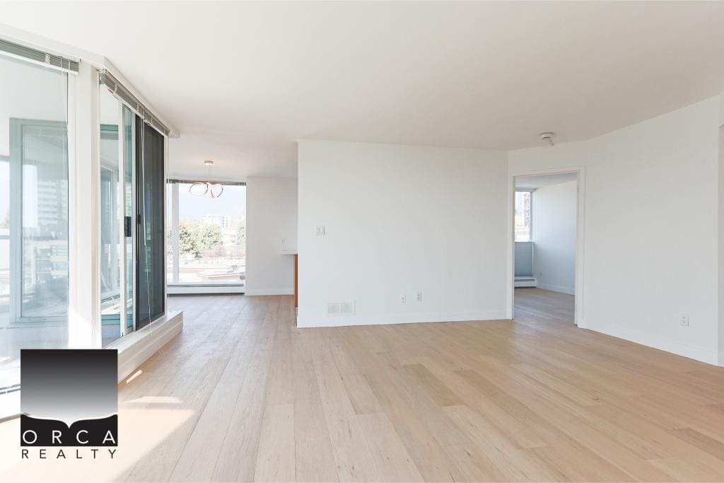 Bright spacious living room with large windows and balcony access in downtown Vancouver. Modern, open-plan layout with light hardwood flooring, ideal for condos or apartments.