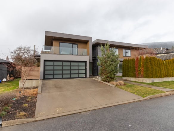 Modern contemporary house with sleek design, large windows, and manicured landscaping in a quiet neighbourhood Vancouver. Features a spacious garage, balcony, and vibrant greenery, ideal for real estate showcasing.