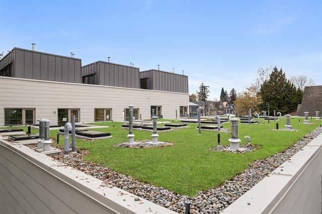 2. Modern rooftop with green grass, utility meters, and HVAC units on a commercial building in Kelowna, BC, showcasing sustainable building design.