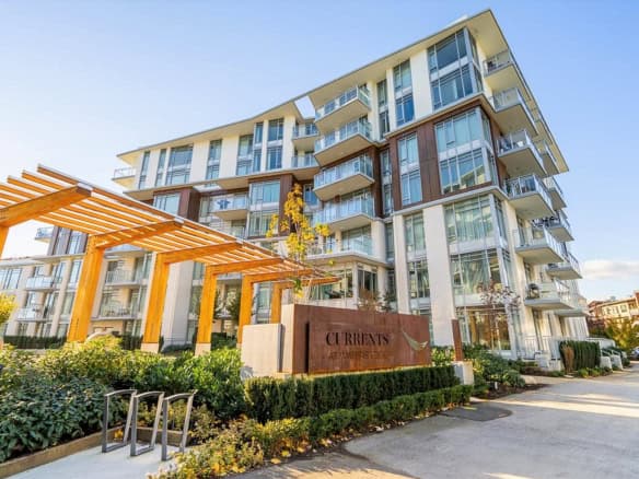 Modern waterfront condominium building with glass balconies and contemporary architecture in Vancouver, BC. Beautiful landscaped exterior with wooden pergola and clear blue sky.