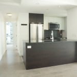 Contemporary kitchen in a modern condo, featuring stainless steel appliances, black backsplash, and minimalist design. Perfect for urban living and homebuyers seeking stylish Vancouver real estate.