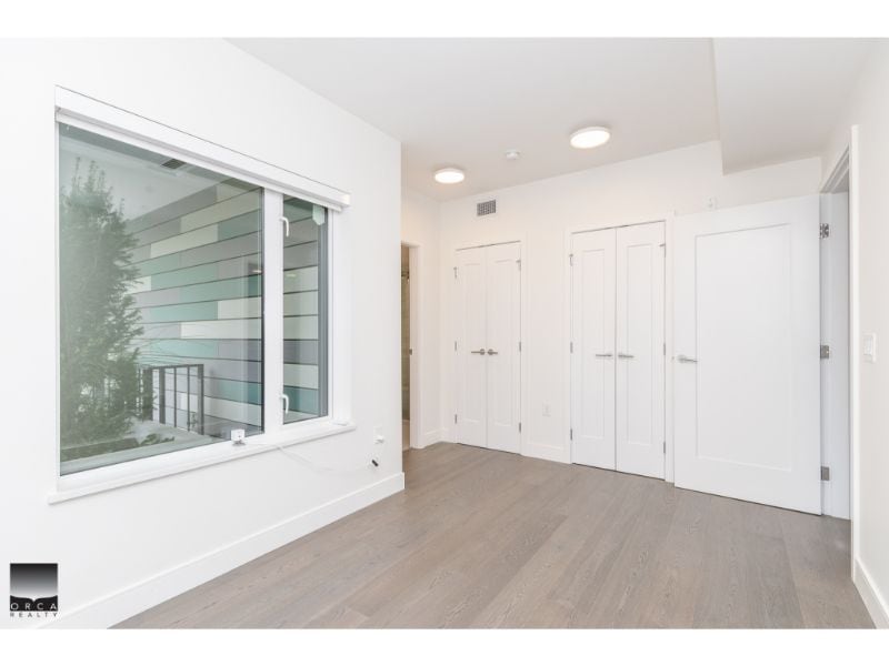 Modern real estate interior with white walls, large window, and spacious closet doors, showcasing a bright, airy space ideal for Vancouver property listings.