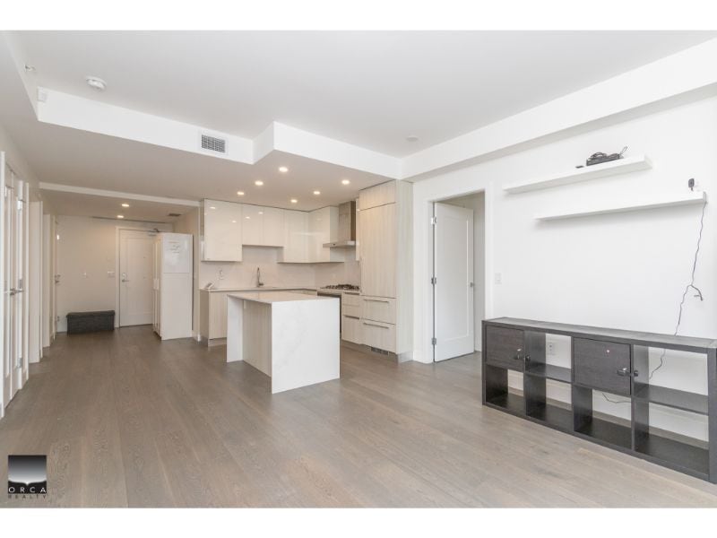 Spacious modern kitchen with white cabinetry and a central island in a contemporary condo or apartment.