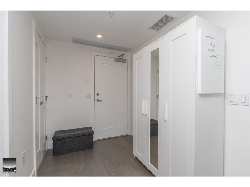 Contemporary white entryway with wardrobe and grey storage bench, modern interior design, ideal for Vancouver area homes, offered by Orca Realty Inc.