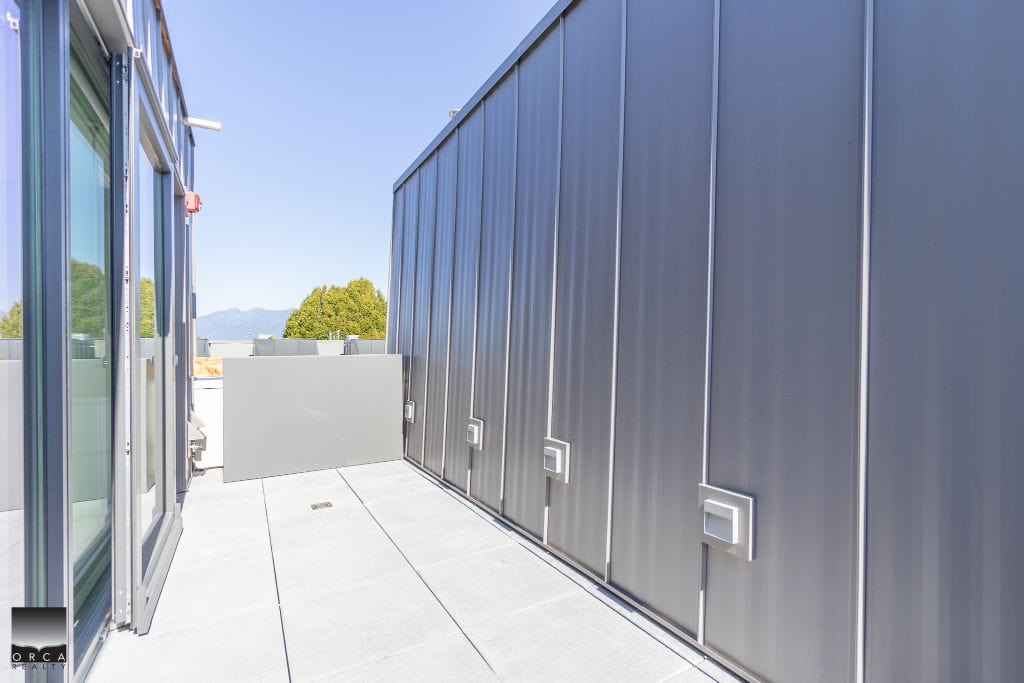 Modern rooftop terrace with sleek grey metal cladding and sliding glass doors, offering outdoor space and stunning mountain views; ideal for residential or commercial properties in BC.