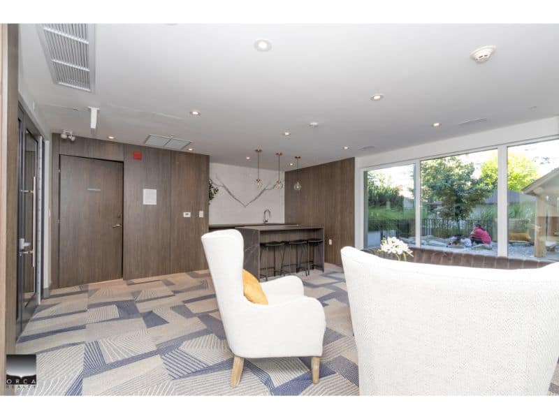 Modern interior lounge area in a contemporary home, featuring comfortable white armchairs, large windows with natural light, and stylish decor for a welcoming home environment.