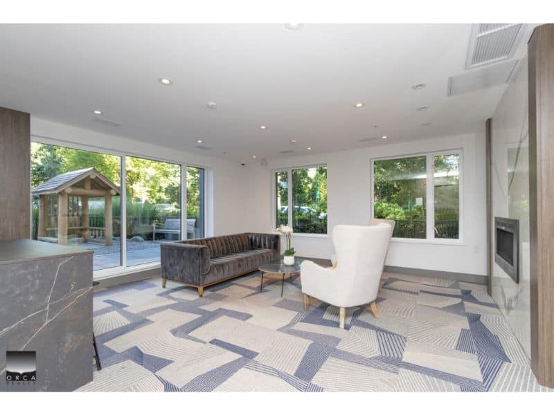 Modern living room with large windows, stylish furniture, and a cozy fireplace, ideal for homebuyers seeking Vancouver real estate options.