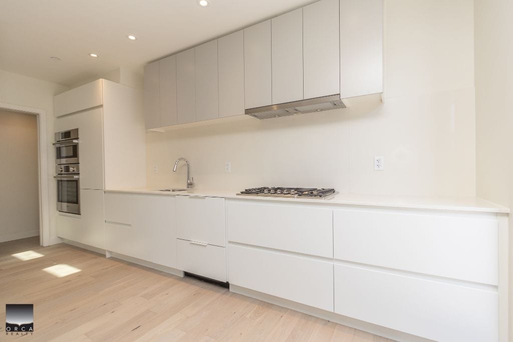 Modern minimalist kitchen with white cabinetry and stainless steel appliances, ideal for Vancouver area real estate, showcasing premium features for potential buyers.