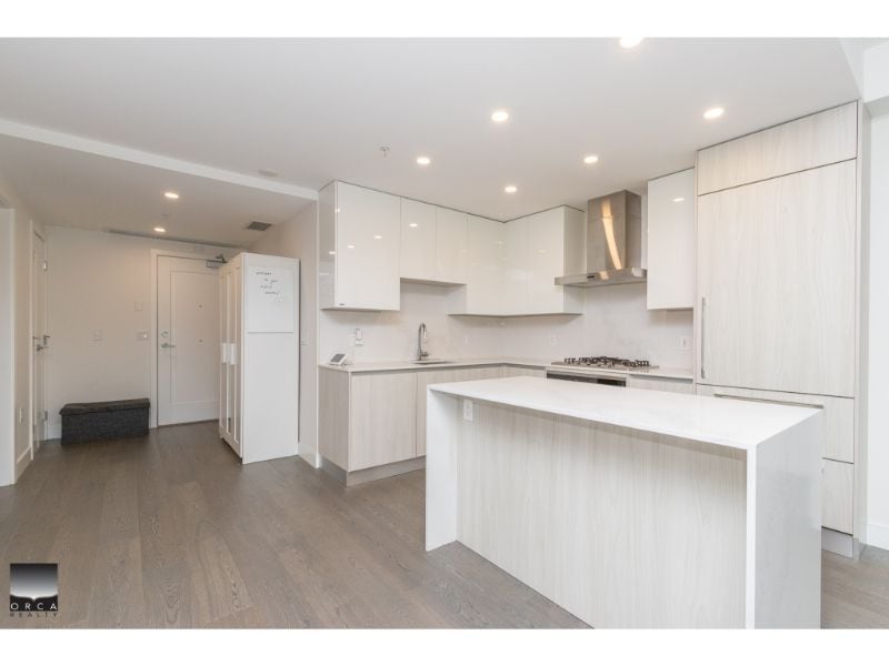 Modern white kitchen with sleek cabinetry and an island, ideal for Vancouver real estate buyers seeking contemporary homes.