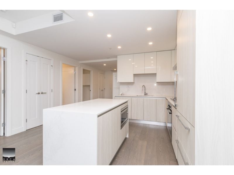 Contemporary white kitchen with sleek cabinetry, modern appliances, and ample counter space in a stylish Vancouver home. Perfect for contemporary living and property showcasing by Orca Realty Inc.