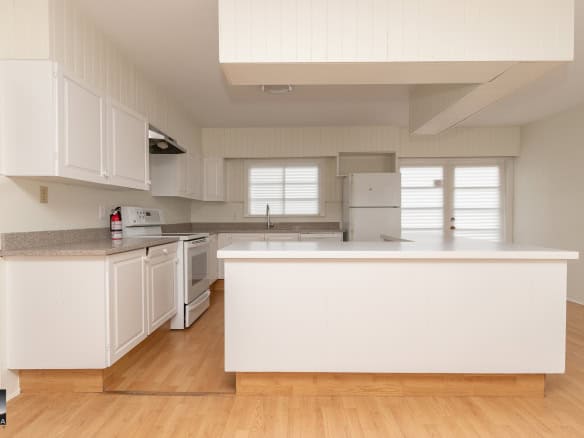 Spacious white kitchen with modern appliances, natural light, and wood flooring, ideal for homebuyers seeking a contemporary and inviting space.