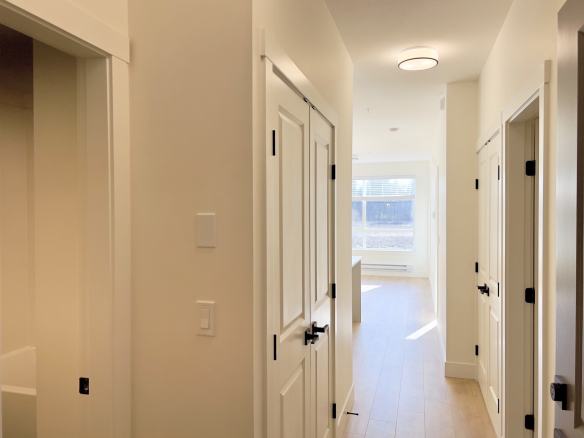 Bright and spacious hallway in a modern home with natural light streaming through large windows, showcasing quality interior design by Orca Realty Inc. in BC.