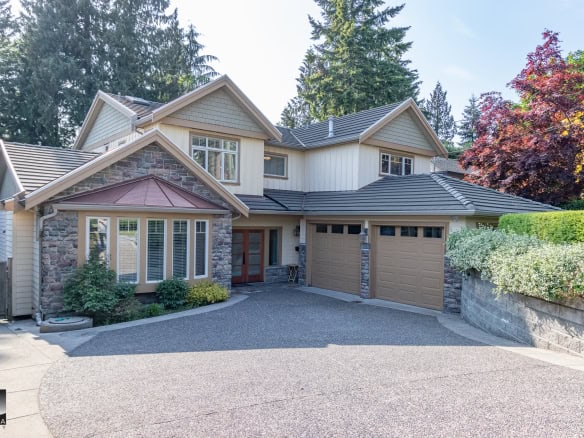 Spacious modern house with a stone and siding exterior, lush landscaping, and a paved driveway, showcasing exquisite homescape design ideal for luxury real estate and property investment in Vancouver.