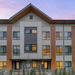 Contemporary multi-family residential building exterior in Vancouver at dusk, showcasing modern architecture and large windows, ideal for real estate investment and property sales in BC.
