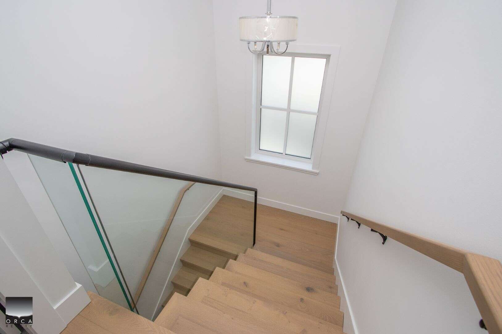 Bright interior staircase with natural wood steps and modern black handrails at Orca Realty Inc., real estate experts in British Columbia, showcasing a contemporary home interior.