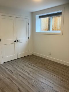Odourlessly clean empty bedroom with white walls and a large window, modern flooring, minimalistic interior design for real estate listing.