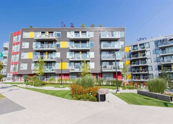 Modern multi-storey apartment building with balconies and landscaped outdoor area in Vancouver, BC. Perfect for Toronto real estate investments and residential living.