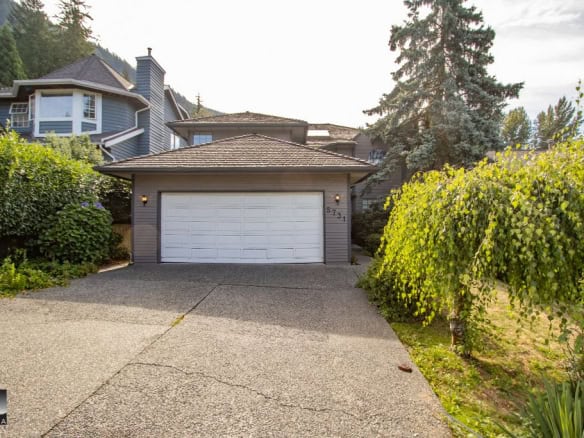 Modern family home with a spacious driveway and lush greenery, located in a scenic neighbourhood. Perfect for families seeking top Vancouver real estate.