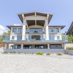 Luxurious modern waterfront home with expansive glass balconies, elegant exterior design, and scenic mountain views, perfect for upscale real estate in BC.