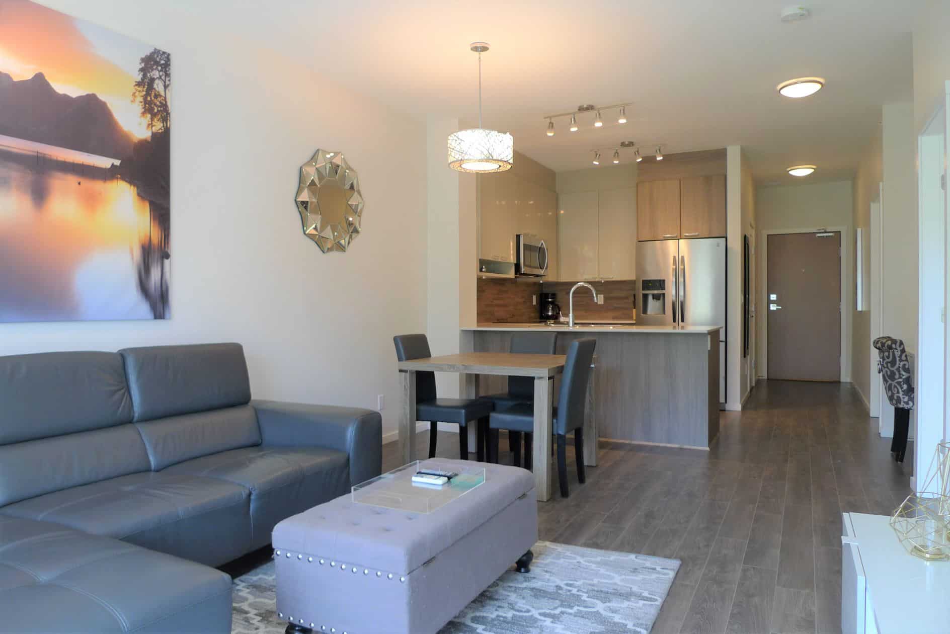 Modern open-concept living room and kitchen in a Vancouver-area condo, featuring stylish decor, stainless steel appliances, and a cozy, inviting atmosphere for homebuyers.