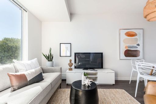 Modern living room interior with large window, comfortable sofa, flat-screen TV, minimalist decor, and artwork, perfect for Vancouver real estate and property listings.
