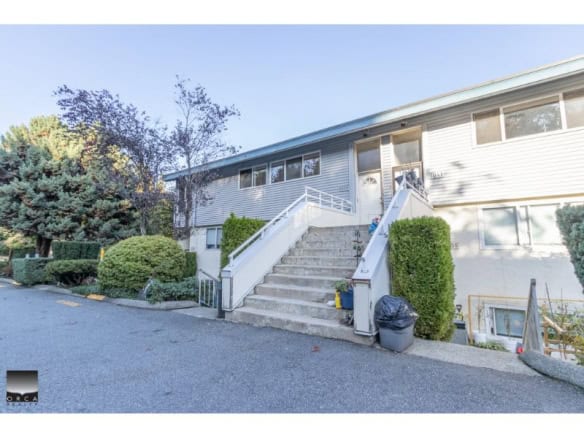 Bright multi-family residential building with accessible concrete stairs, surrounded by well-maintained shrubs and trees in a desirable neighbourhood, listed by Orca Realty Inc.