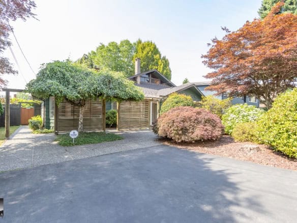 Spacious residential driveway with lush landscaping and mature trees, showcasing a charming home exterior in Vancouver, BC, ideal for local real estate listings and property marketing.