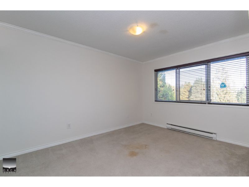 Bright empty bedroom with large window, white walls, natural light, and beige carpet, ideal for Vancouver real estate buyers seeking move-in ready condo or apartment.