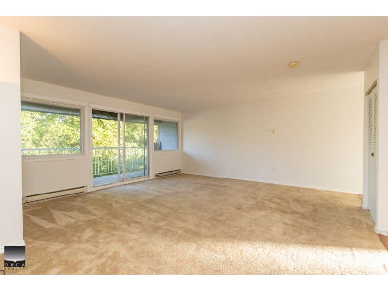 Bright spacious living room with large windows and balcony access, ideal for comfortable apartment living in Vancouver.