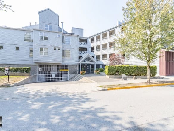 Modern multi-family residential building with parking garage, landscaped entry, and surrounding greenery in a peaceful neighbourhood - Orca Realty Inc.