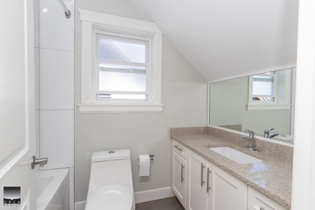 Bright modern bathroom with white cabinets, granite countertop, and a large mirror, showcasing clean and minimal design, perfect for Toronto real estate listings and property marketing.