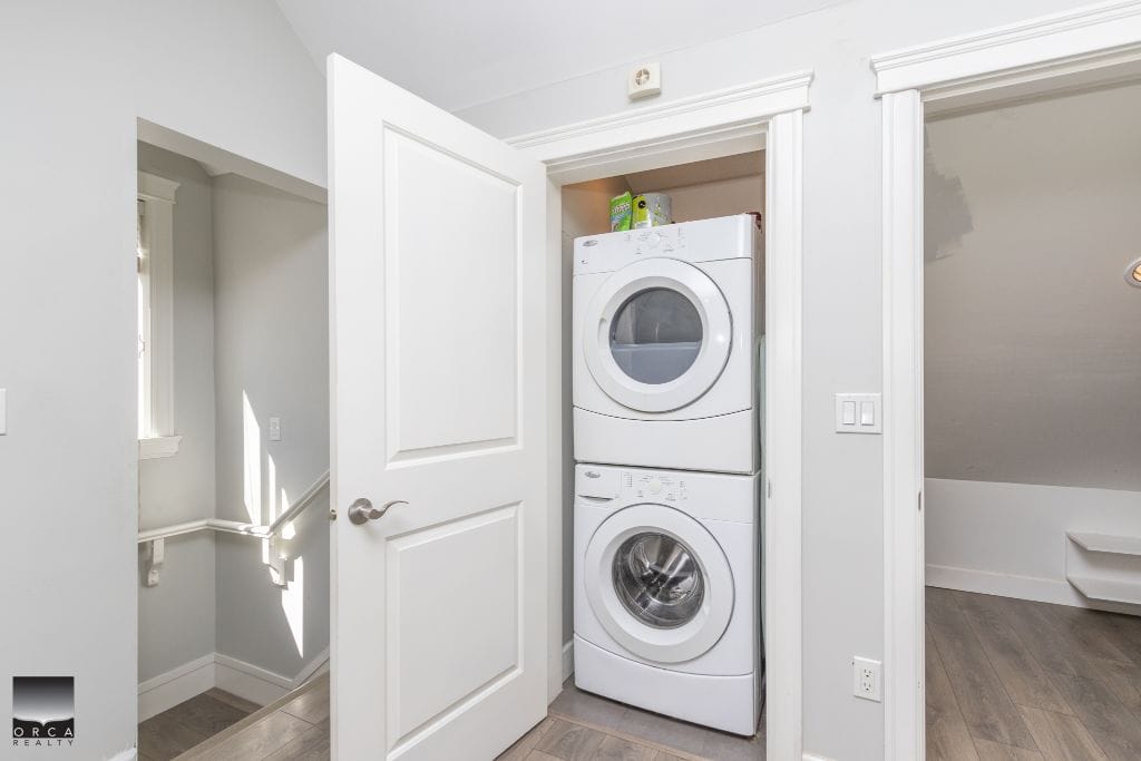 Stacked washer and dryer in a laundry closet within a modern home.
