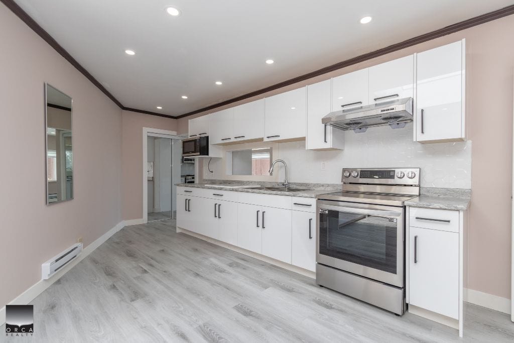Modern white kitchen with stainless steel appliances, granite countertops, and ample cabinet storage, perfect for family living and entertaining.