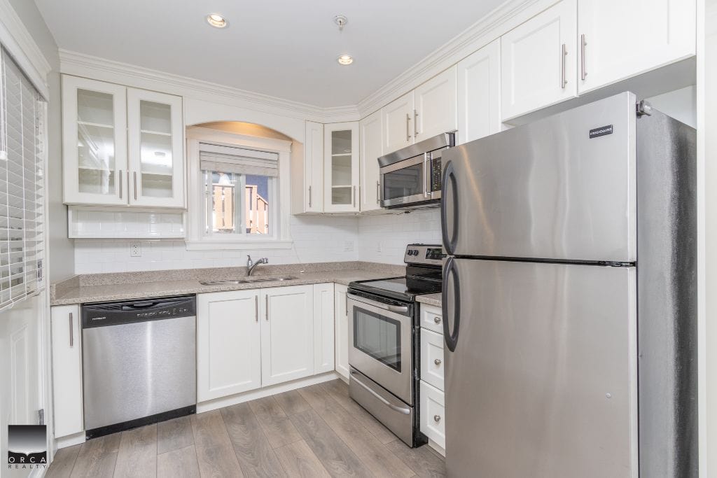 Contemporary white kitchen with stainless steel appliances, granite countertops, and modern cabinetry, perfect for Vancouver Island real estate buyers.