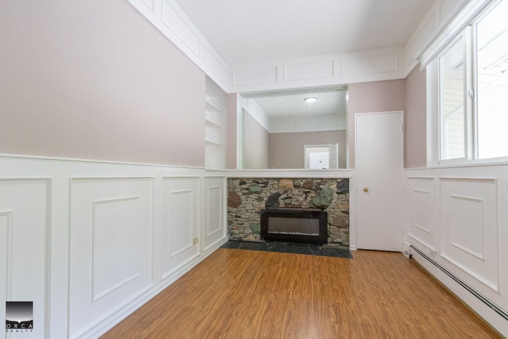 Cozy living room with natural light, stone fireplace, and elegant wainscoting, perfect for family gatherings and relaxing at home in a Vancouver-area property.