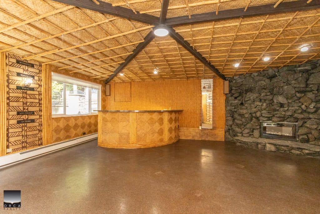 Spacious interior of a rustic home with wooden and stone accents, showcasing a cozy fireplace and bar area, perfect for real estate listings in Vancouver, BC.