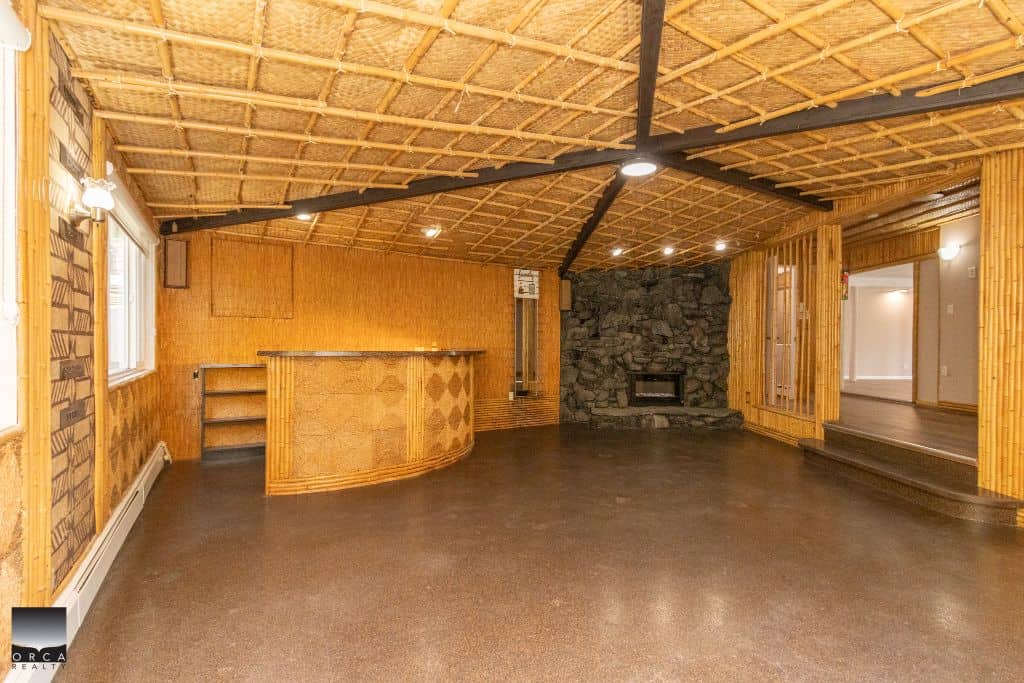 Wood-paneled interior with stone fireplace and bar area, perfect for cozy gatherings and entertaining in a rustic-style home.