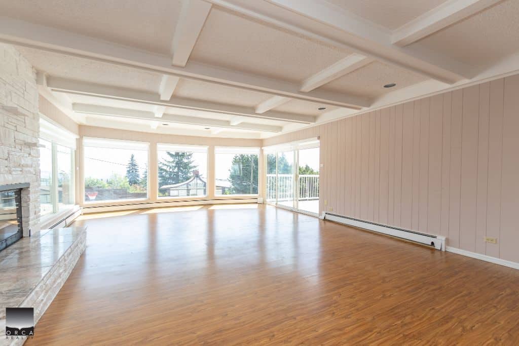 Bright spacious living room with large windows, hardwood flooring, and scenic views, ideal for Vancouver Island real estate and family living.