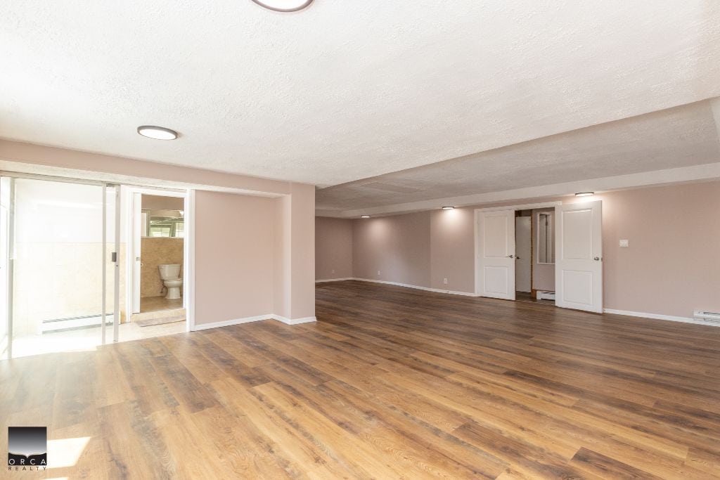 Spacious basement living area with hardwood floors and modern interior in a Vancouver-style home, perfect for family living and entertainment.