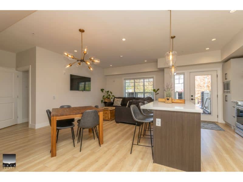 Modern open-concept living and dining area in a contemporary Vancouver home with hardwood flooring, stylish lighting, and a spacious kitchen with an island for family gatherings.