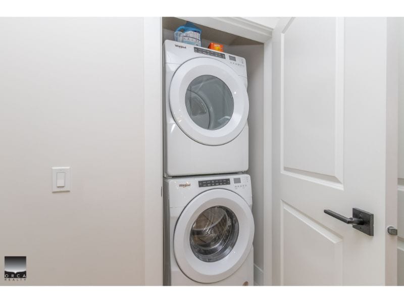 Stacked white washing machine and dryer in laundry closet, modern home appliances for easy laundry management, located in a clean, well-lit utility space.