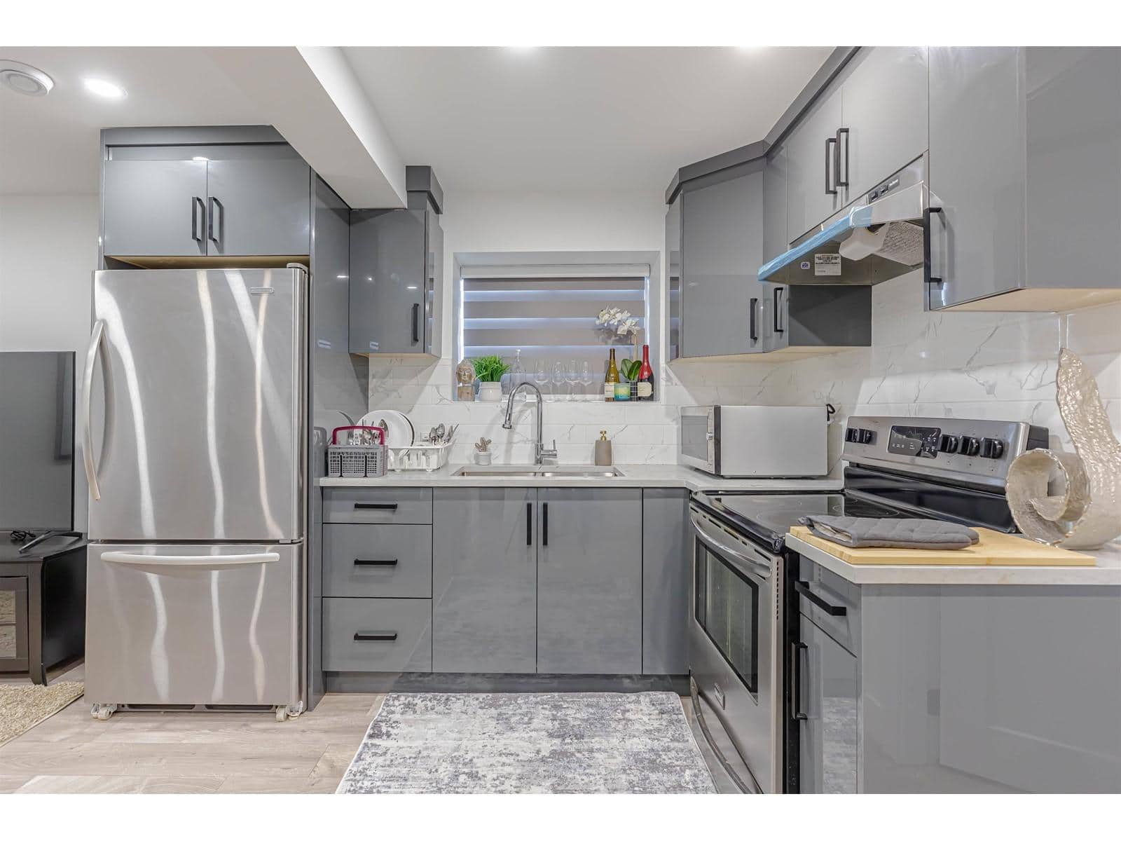 Modern grey kitchen with stainless steel appliances, marble backsplash, and sleek cabinetry, perfect for home cooking and entertaining.