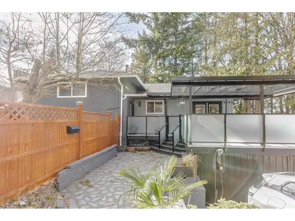 Charming Vancouver home with modern updates, outdoor patio area with a wooden fence, stone pathway, and lush trees, perfect for relaxed outdoor living and entertaining.